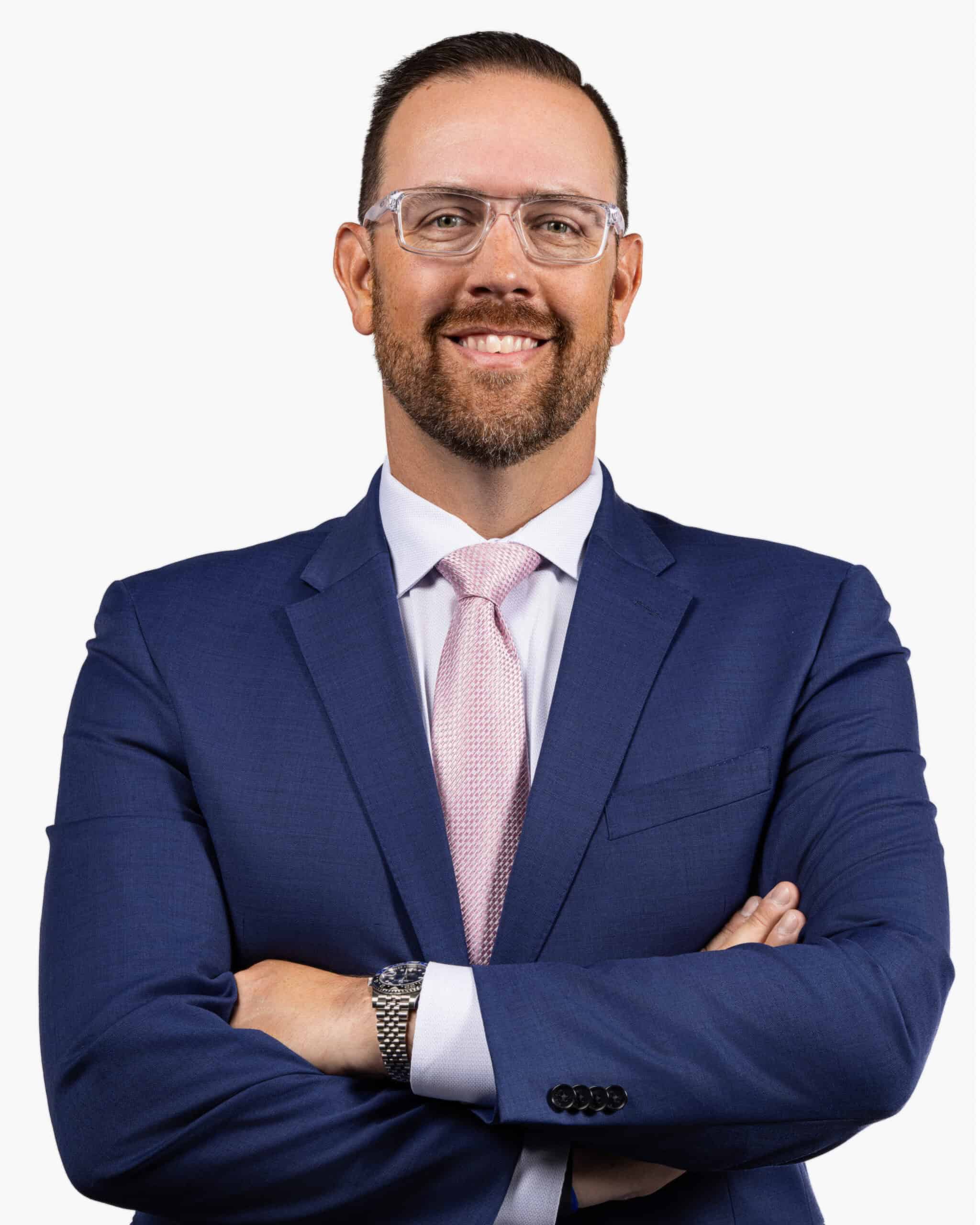 Close-up of confident man wearing blue suit, pink tie, and clear glasses for corporate photography.